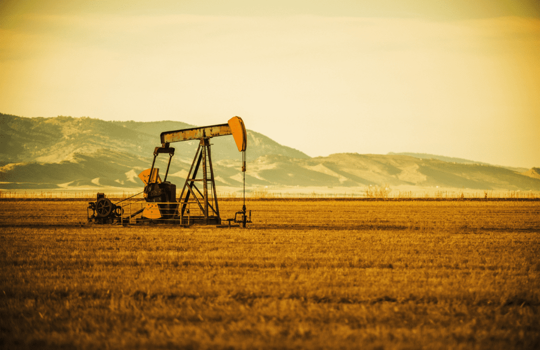 Oil drill in a prairie with mountains in the background